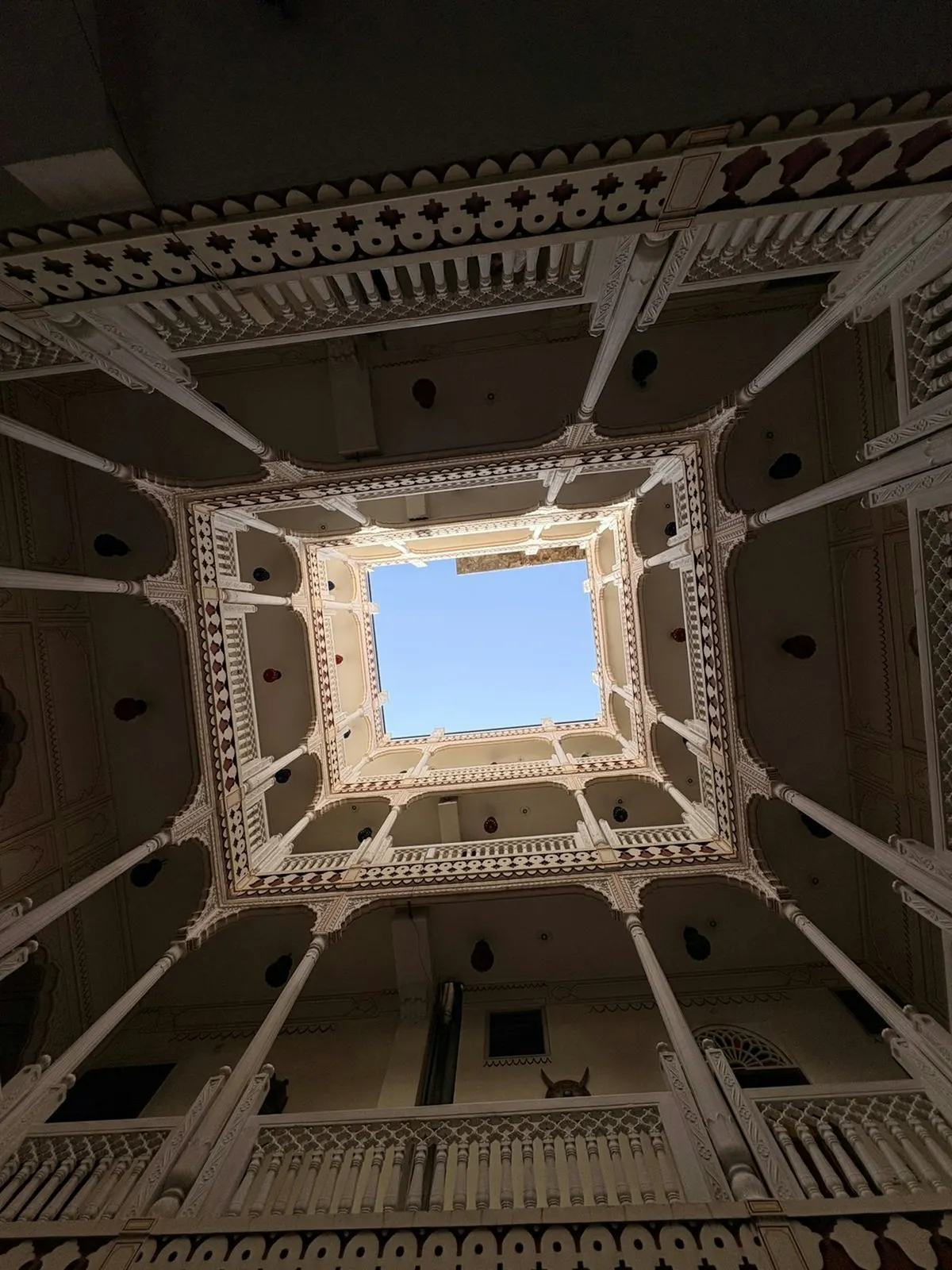 A haveli courtyard seen from below, galleries rising to a square of sky