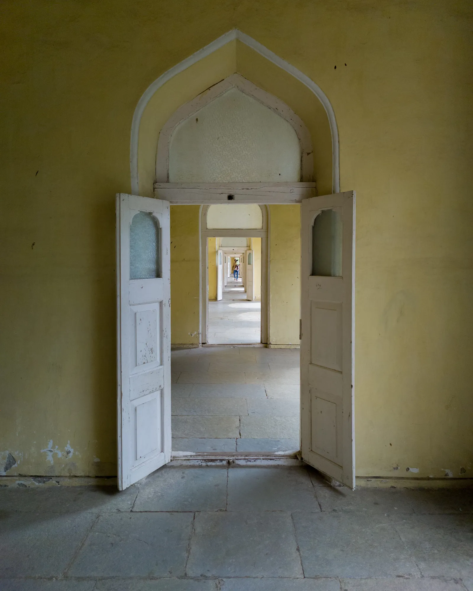 A run of open palace doorways receding in line, empty and quiet